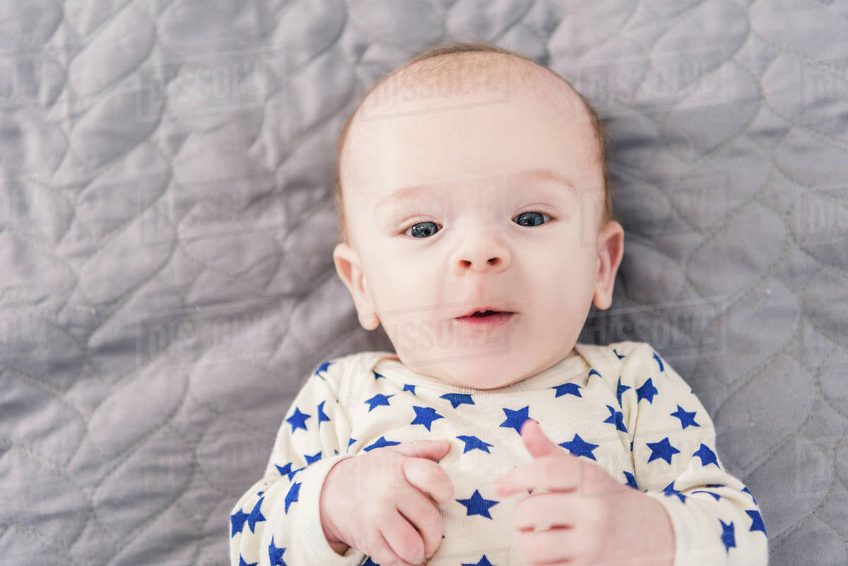 Overhead view of adorable little baby lying on grey blanket Stock
