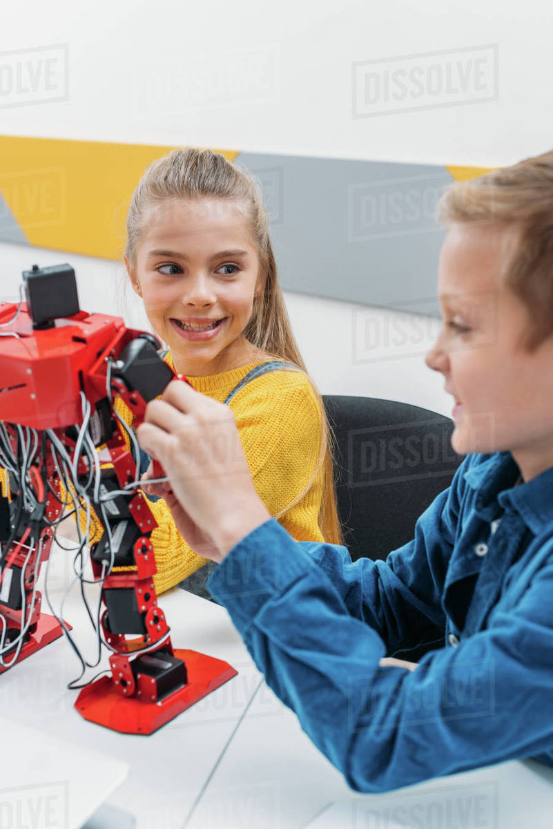 Smiling schoolchildren programming robot together during stem ...