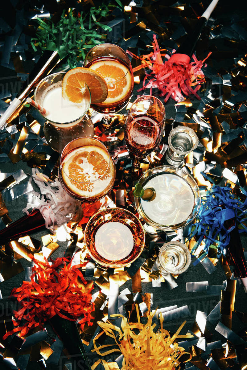 Top view of various alcoholic cocktails and party horns on table