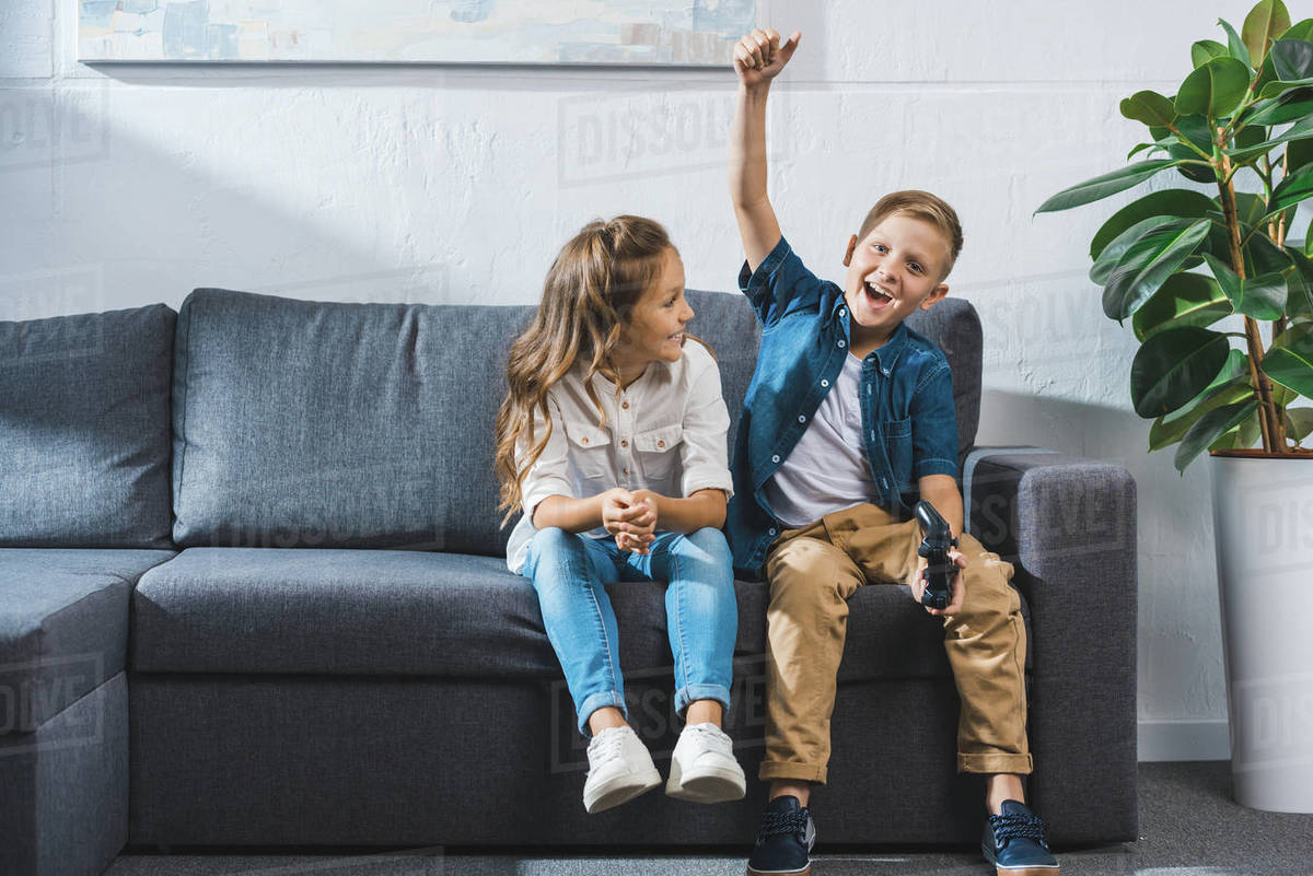 Happy children playing video game with joystick at home Stock Photo