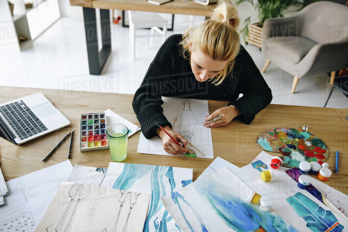 Overhead view of young female fashion designer drawing watercolor