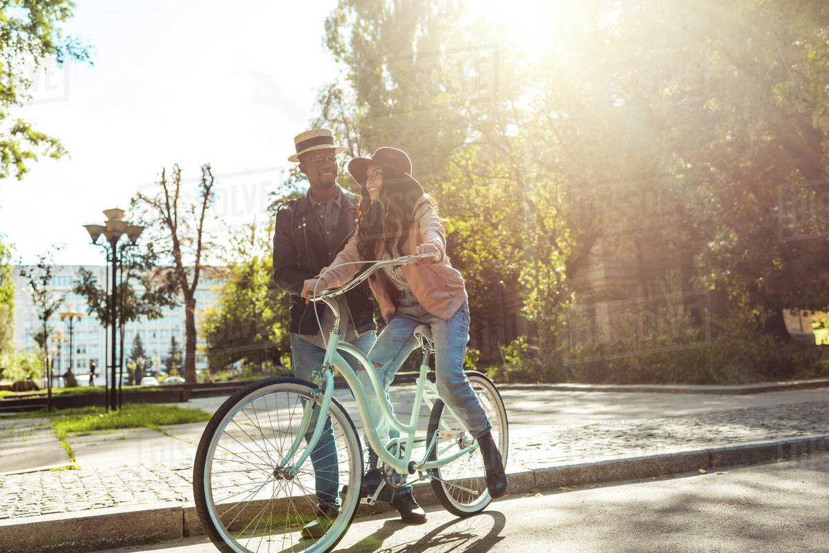 Boyfriend helping girlfriend riding a bike in a park Royalty
