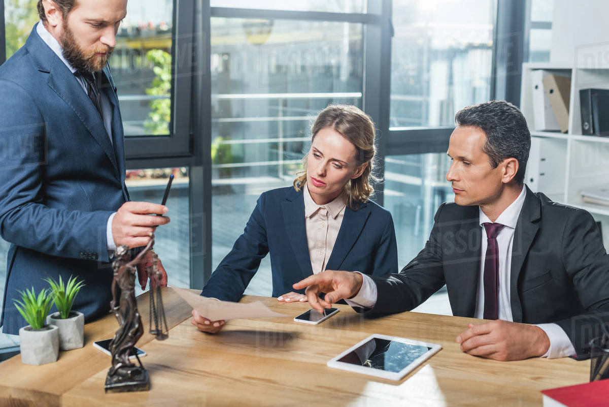 Group of lawyers in suits discussing contract together in office