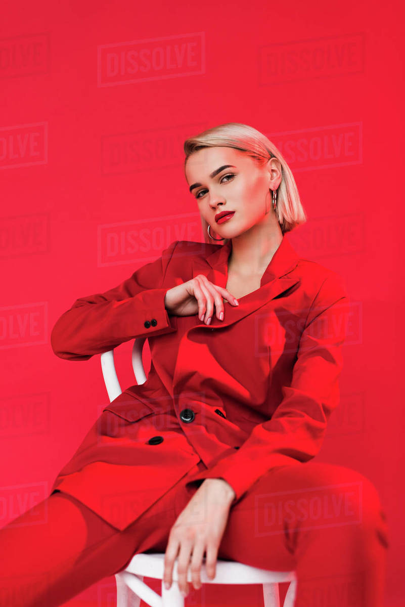 Fashionable elegant girl posing in red suit, isolated on red