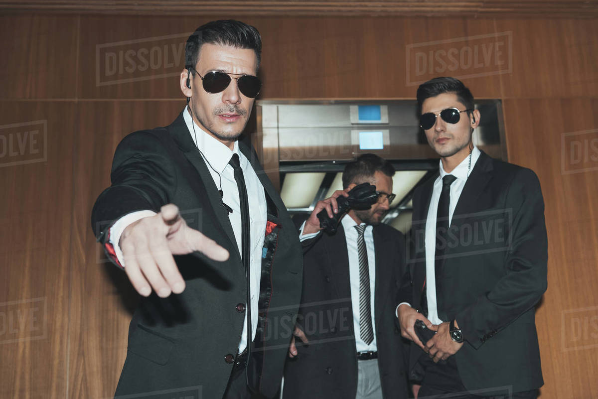 Bodyguards stopping paparazzi when celebrity going out from elevator