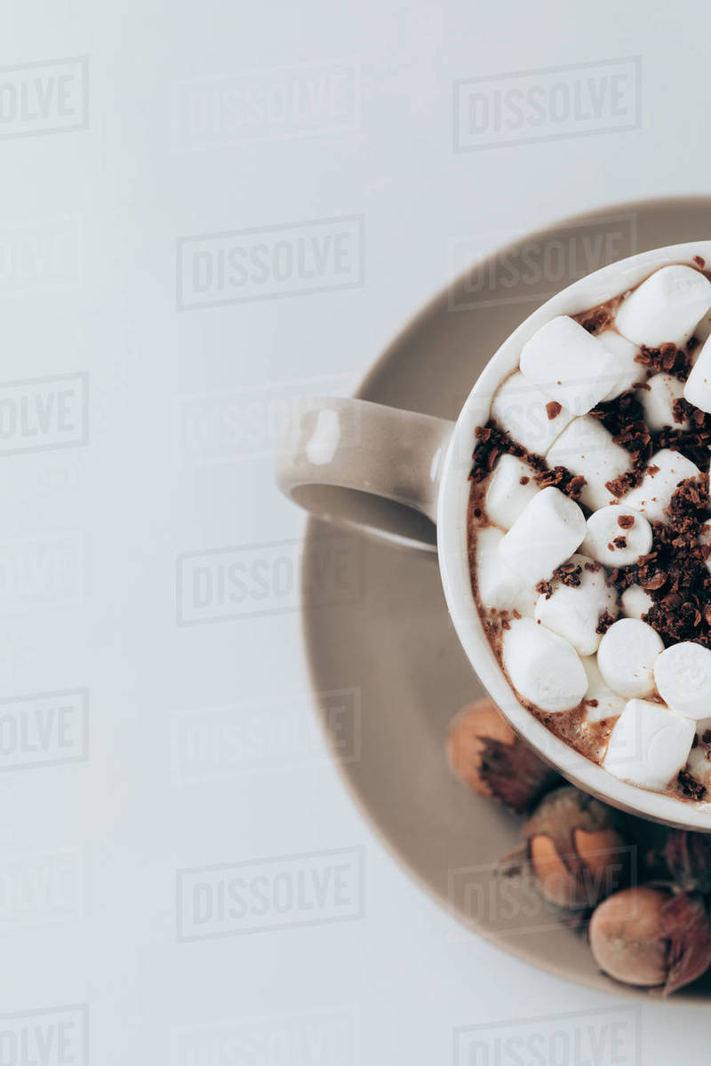 Top view of aromatic hot cacao with marshmallows, chocolate and walnuts