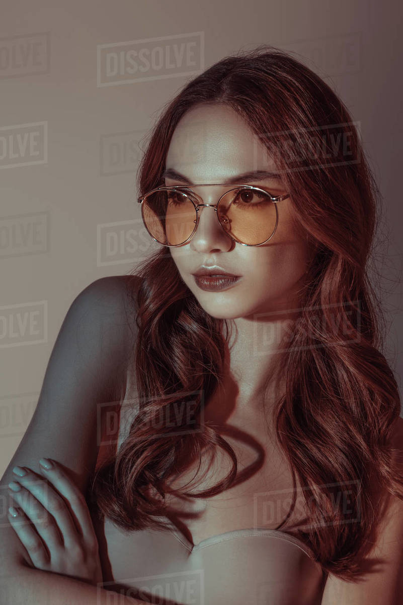 attractive girl posing in yellow sunglasses, isolated on grey Stock