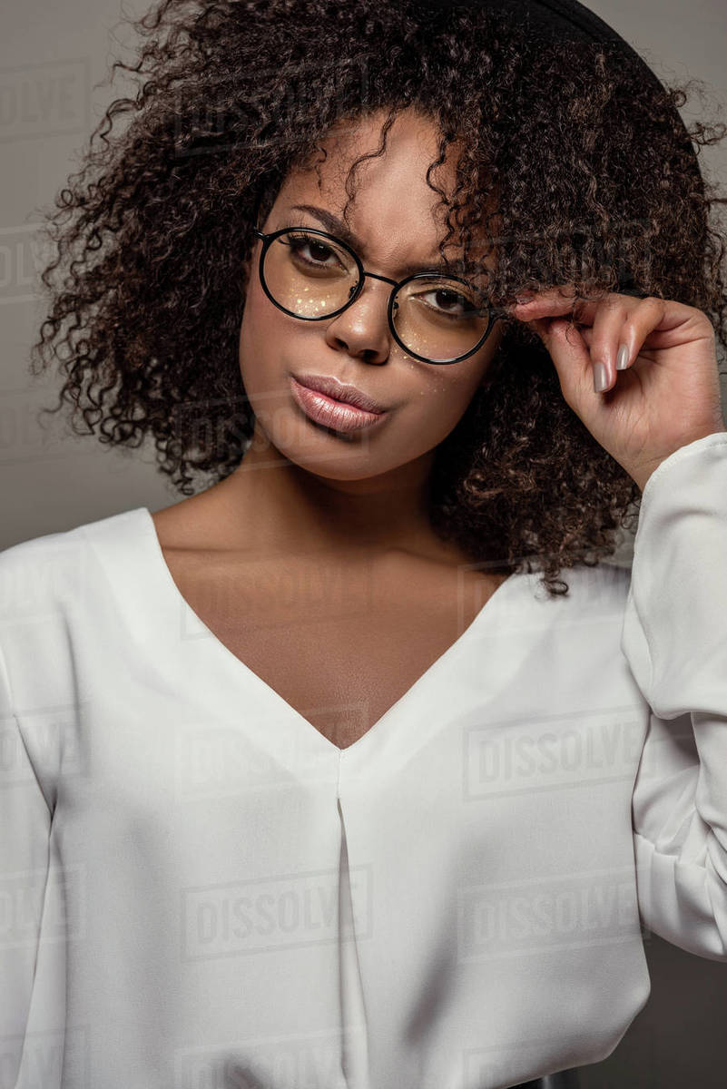 Young African American Woman In White Shirt Touches Her Eyeglasses