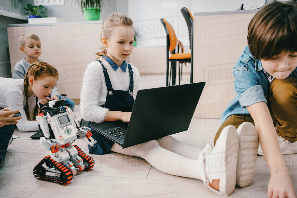 kids programming robot while sitting on floor at stem education class ...