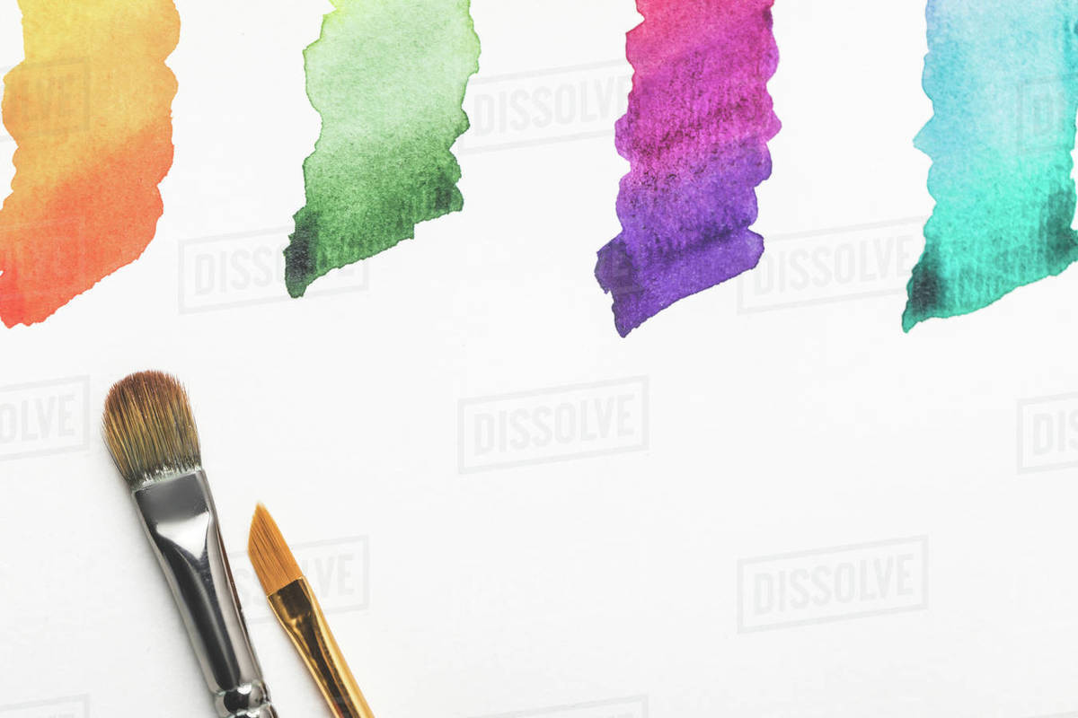 Closeup view of paintbrushes and colorful bright paint strokes