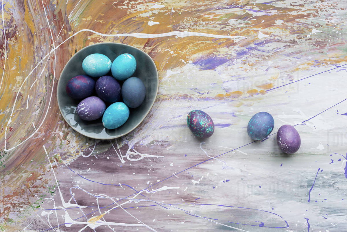 Painted chicken eggs in bowl and on stained background Stock Photo