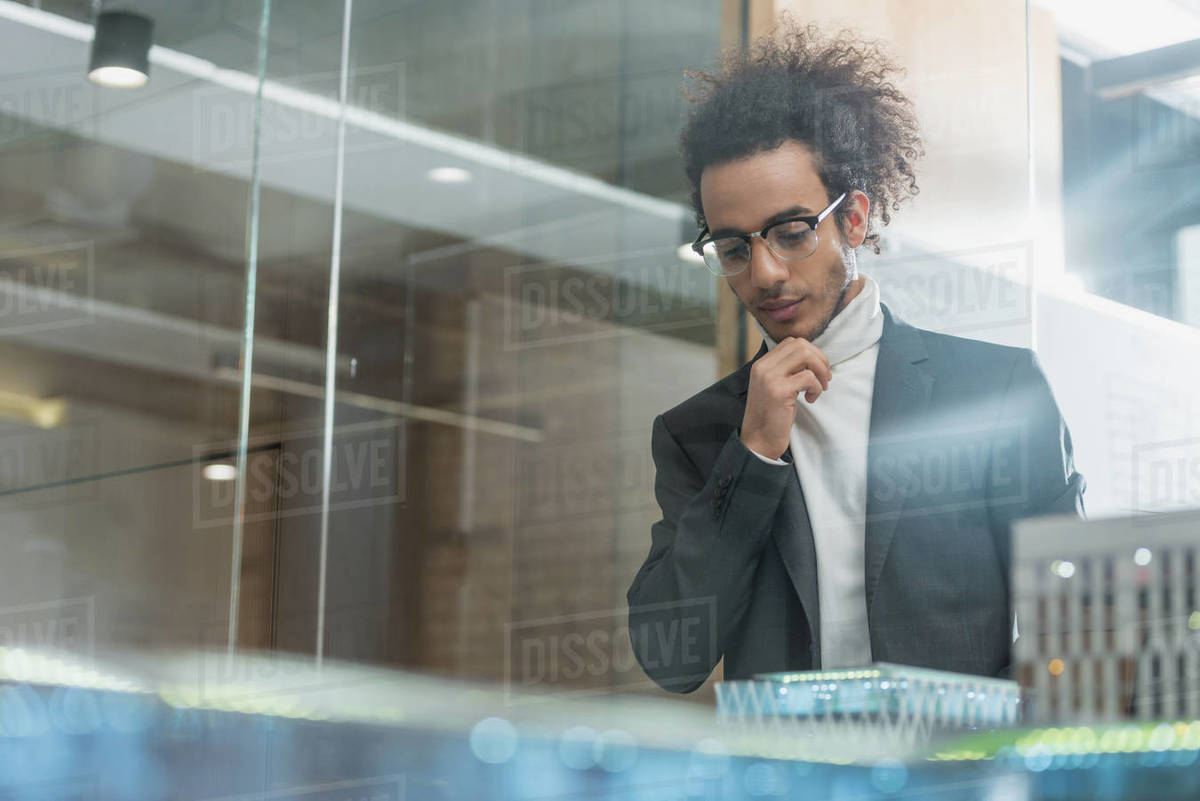 Thoughtful young architect in suit near buildings miniature model at office Royalty-free stock photo