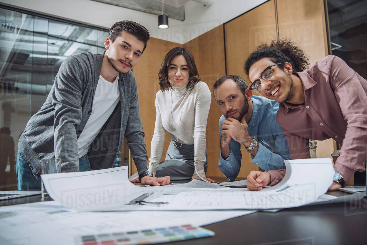 Group of successful architects discussing plans and looking at camera at office Royalty-free stock photo