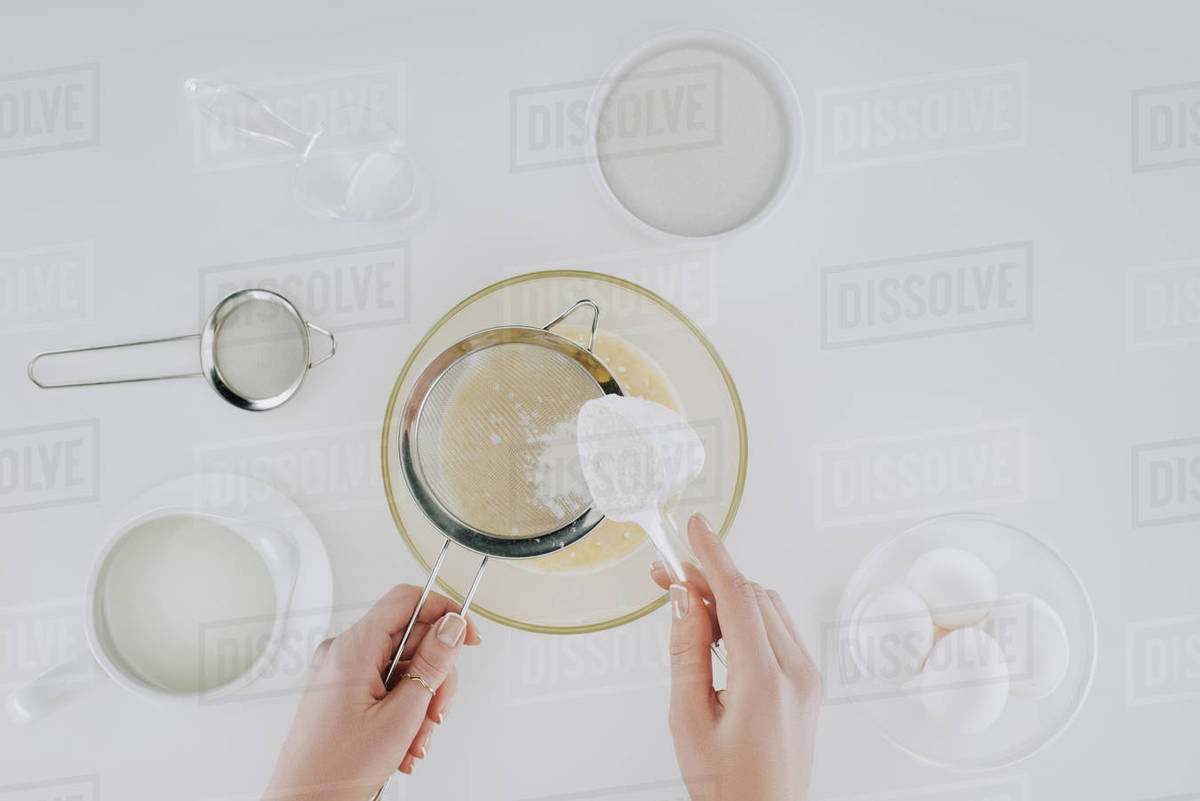 Top view of person sifting flour while cooking pancakes isolated on