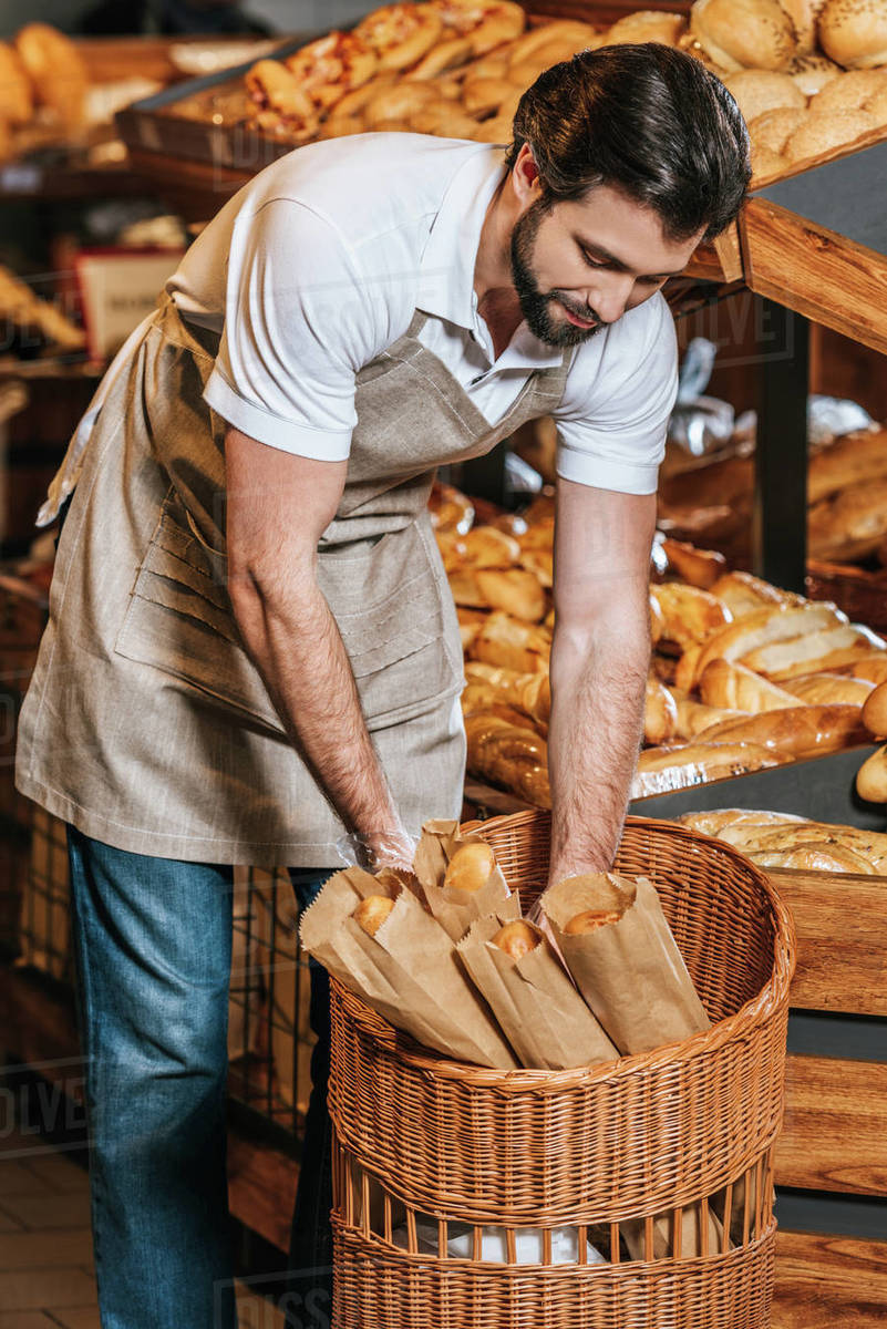 Male shop assistant arranging fresh pastry in supermarket Stock Photo