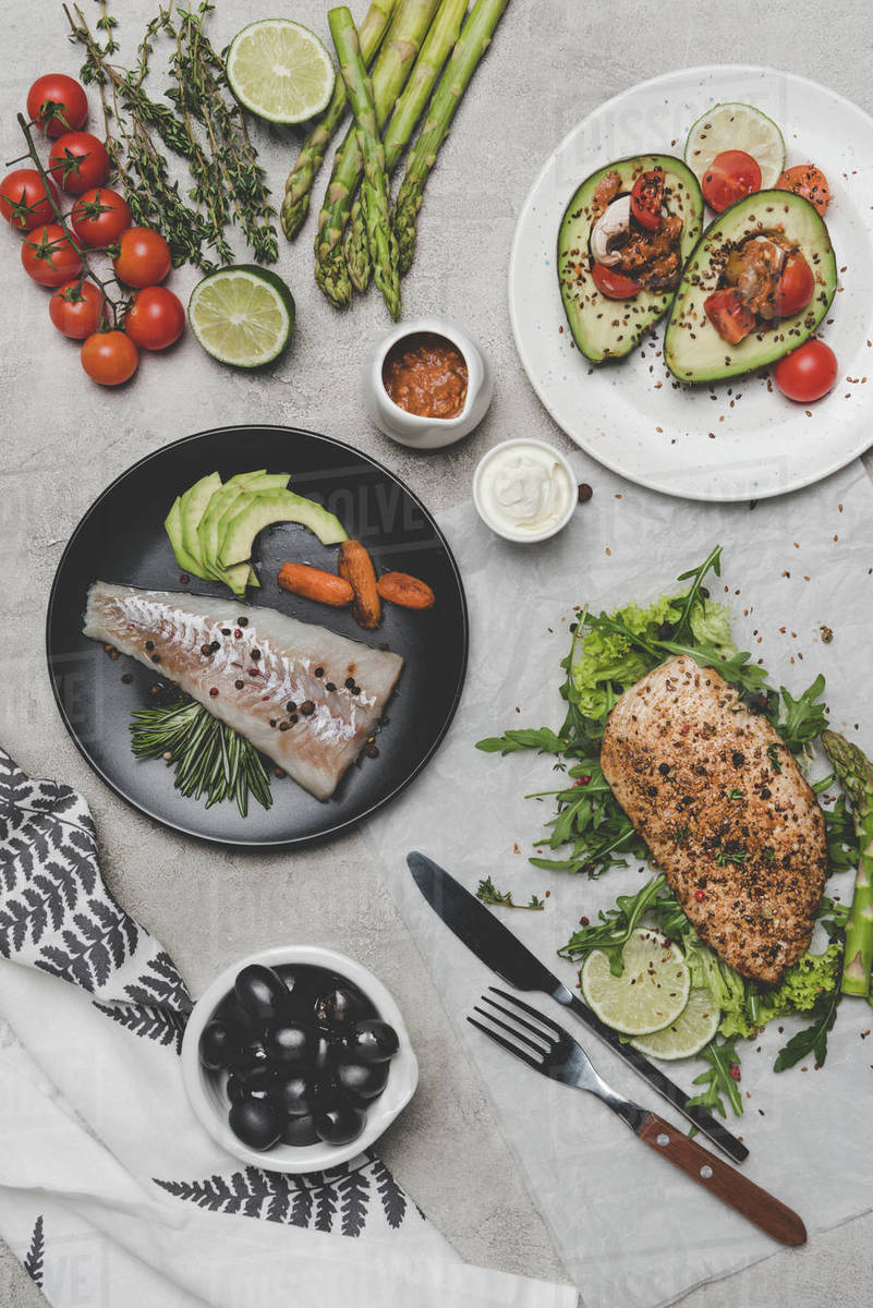 Top view of healthy dishes with fish, meat and avocado on grey Stock