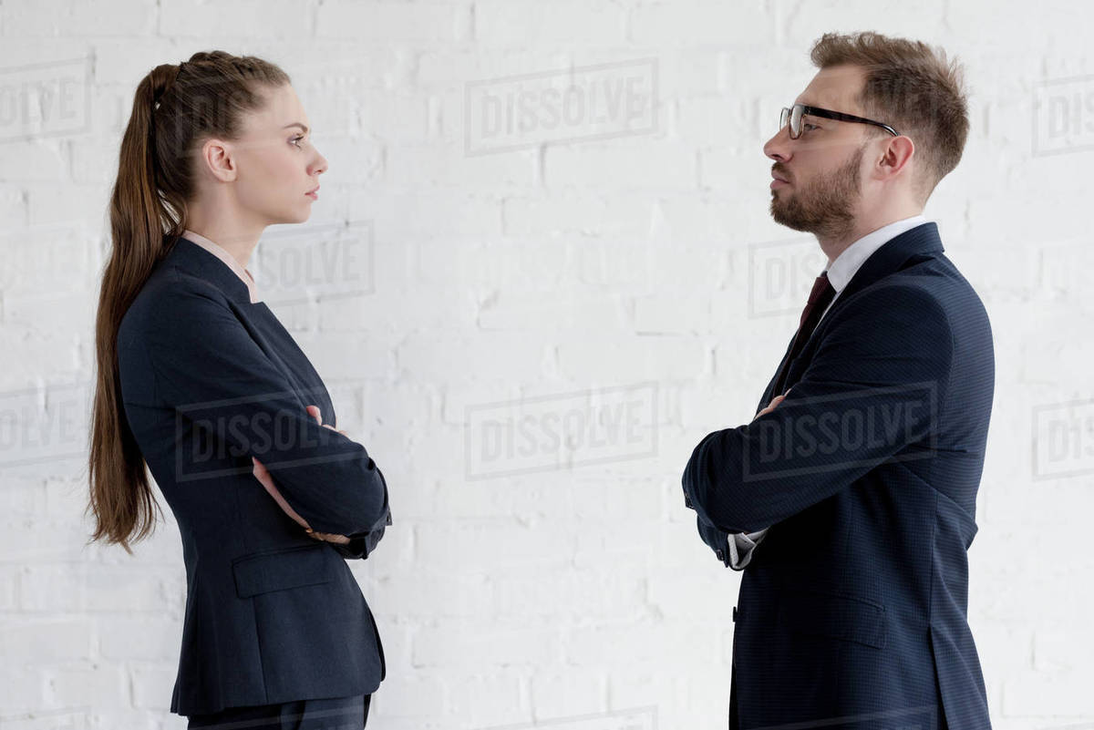 Serious businesspeople with crossed arms looking at each other Stock