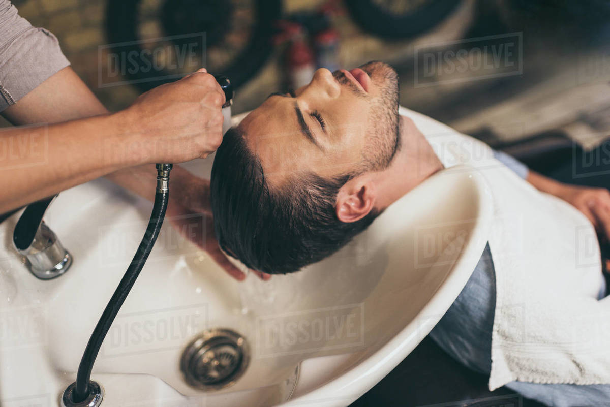 Cropped View Hairstylist Washing Clients Hair In Barber Shop
