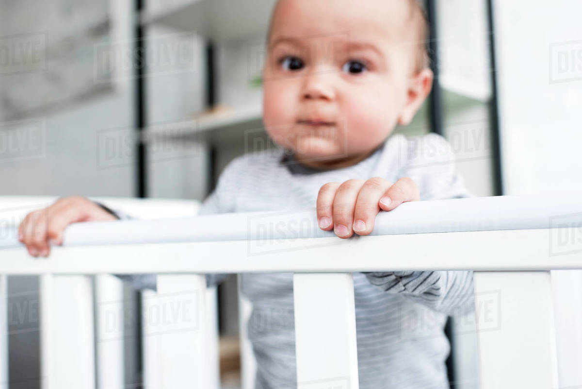 Closeup portrait of adorable little child in baby cot looking at