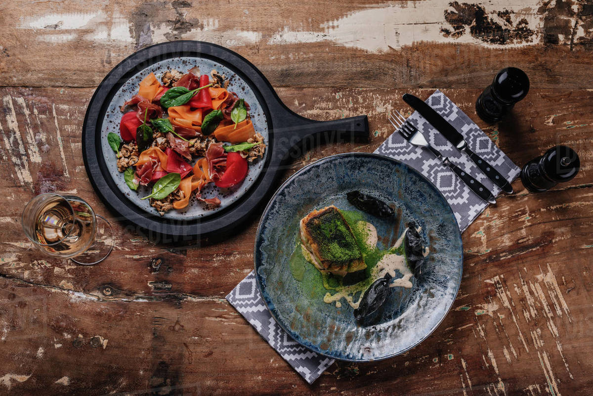 Top view of delicious dishes on plates on wooden table Stock Photo Dissolve