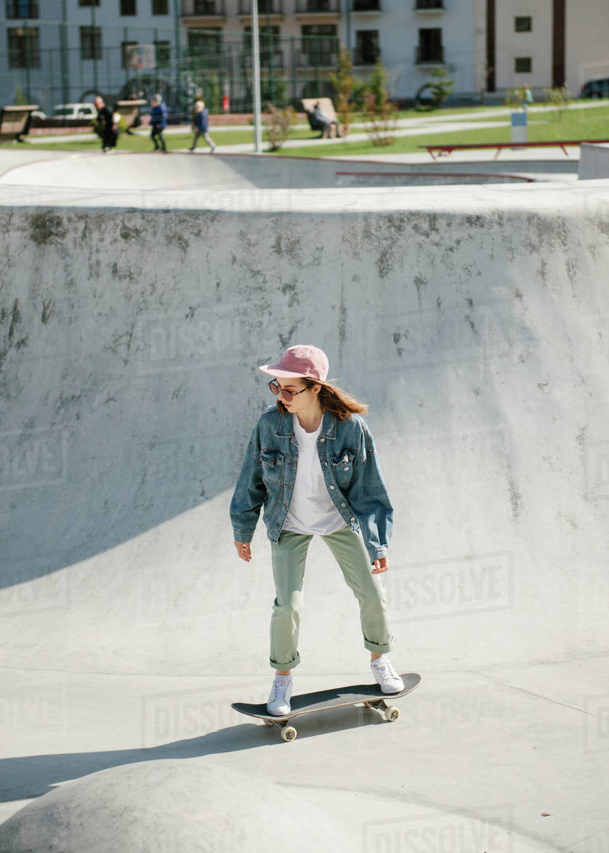 Young woman doing skateboarding trick outdoor Stock Photo Dissolve