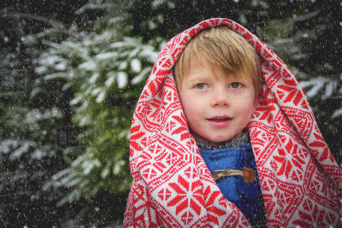 Portrait of smiling boy wrapped in a blanket in the snow Stock Photo