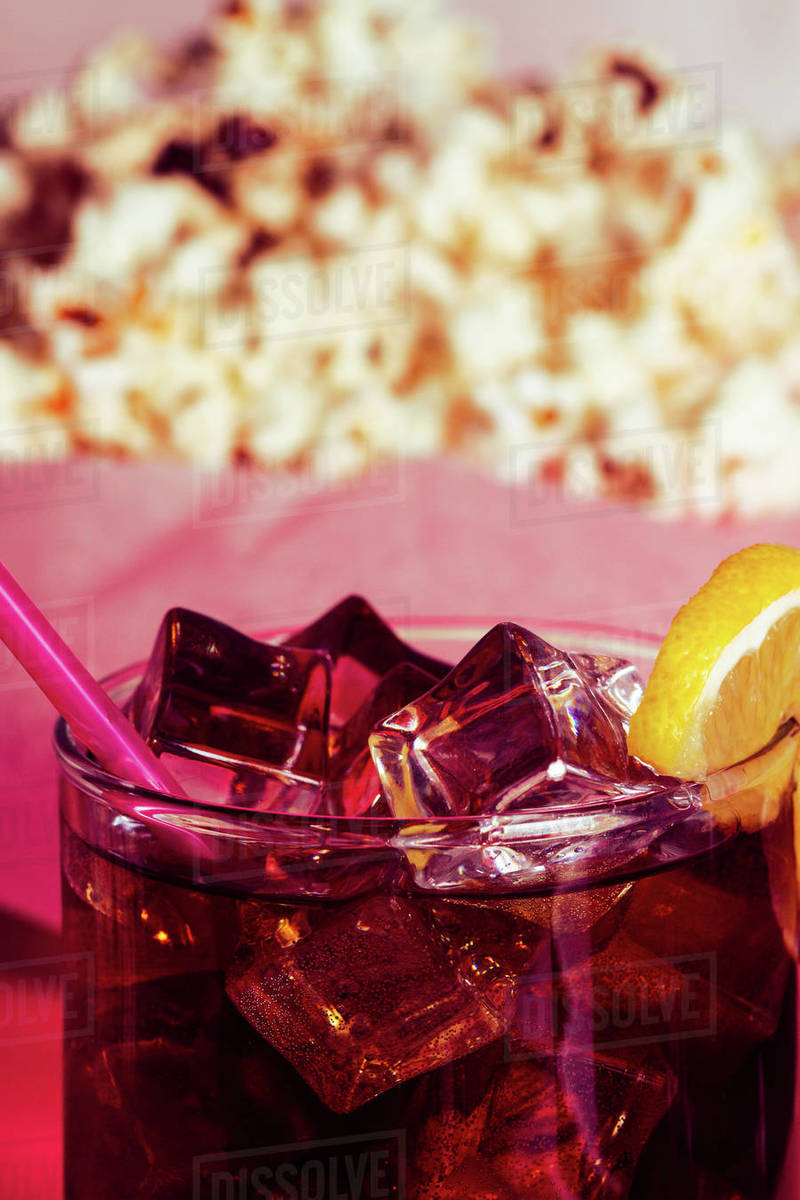 Popcorn in bowl near drink in glass with ice and lemon Stock Photo Dissolve