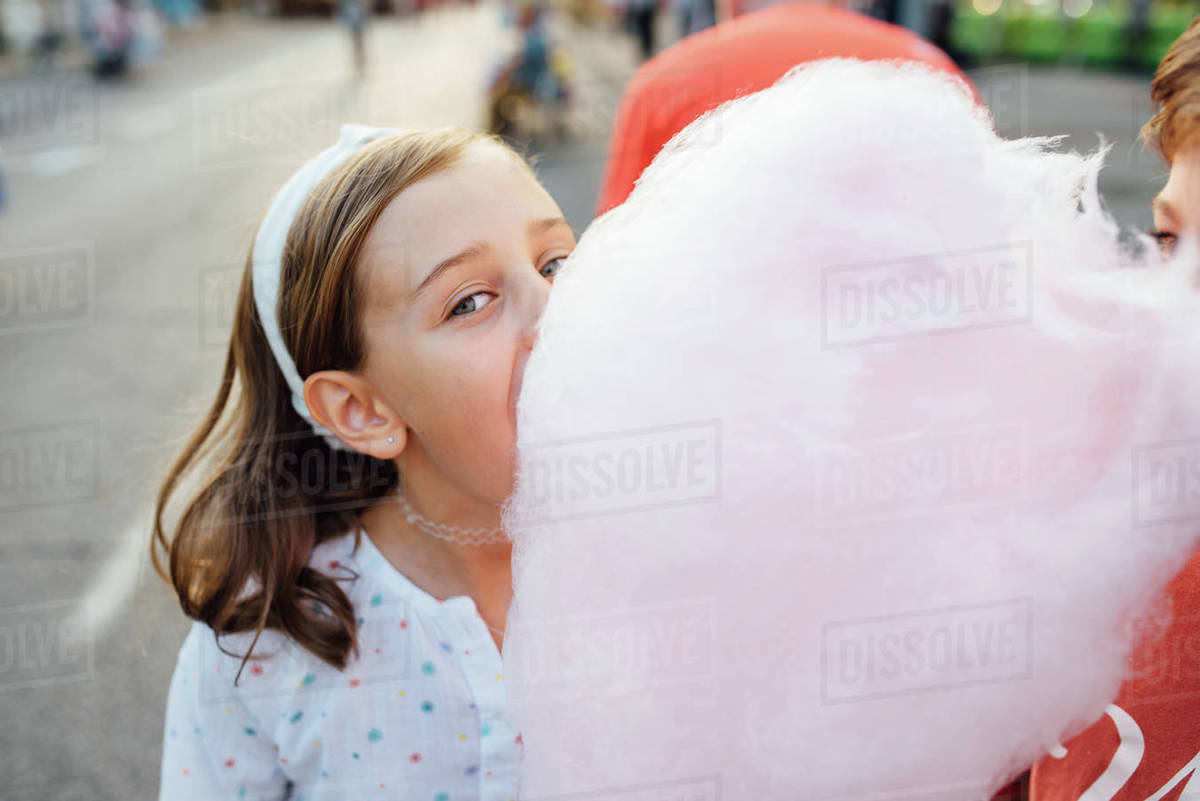 Cheerful girl eating cotton candy on street Stock Photo Dissolve