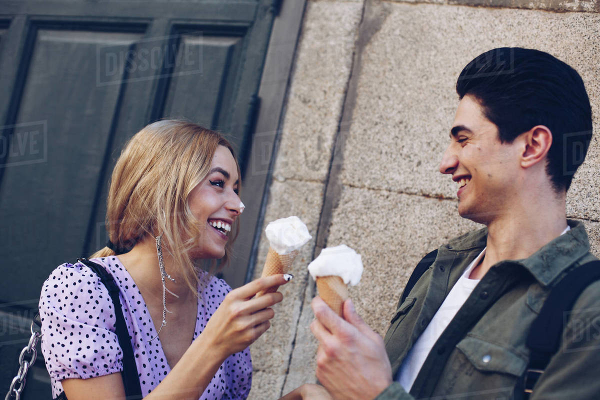 Cheerful young attractive woman and boyfriend eating of ice