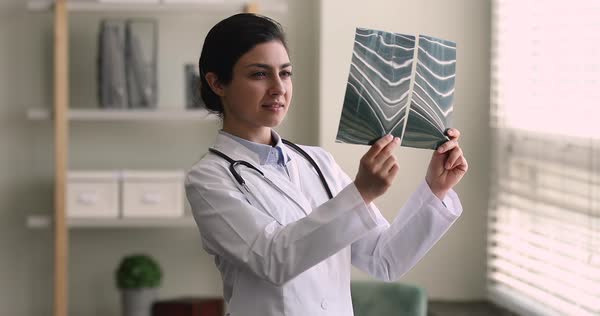 Indian female radiologist doctor examining x-ray film at hospital ...