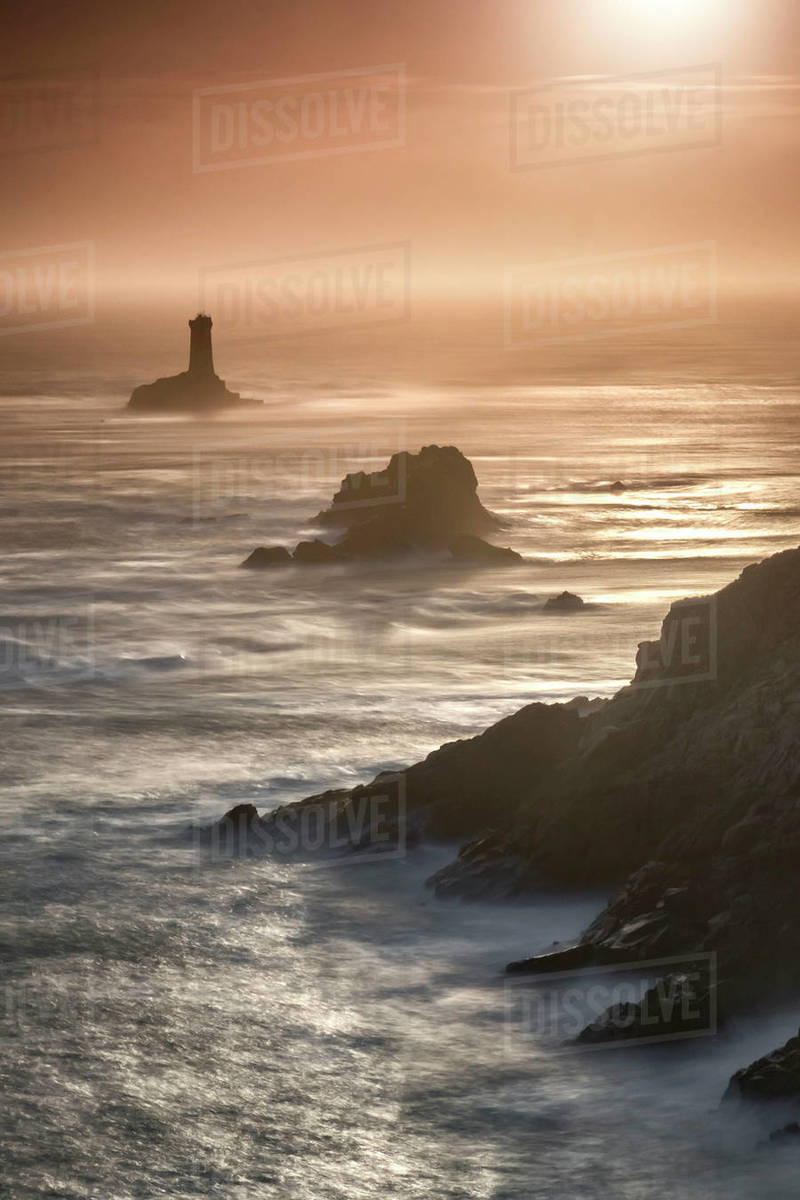Pointe du Raz lighthouse and cliffs at sunset in Finisterre, Brittany