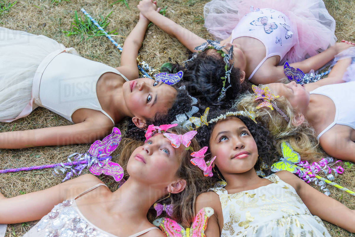 Group of young girls dressed as fairies, lying in circle, heads together Royalty-free stock photo