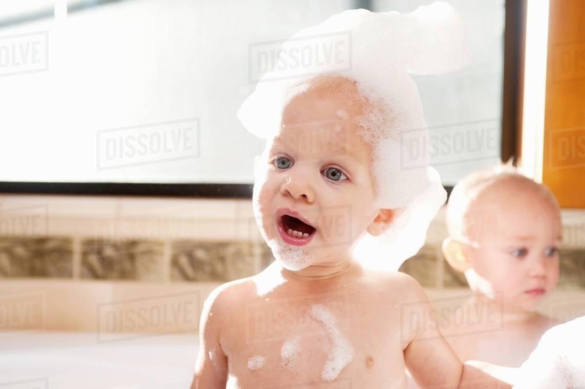 Baby boy covered in soap suds in bath Stock Photo Dissolve