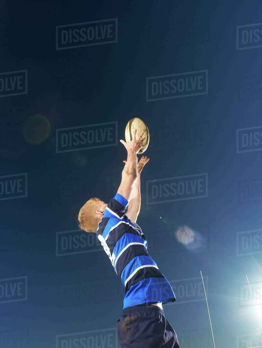 Rugby player reaching to catch ball Stock Photo Dissolve