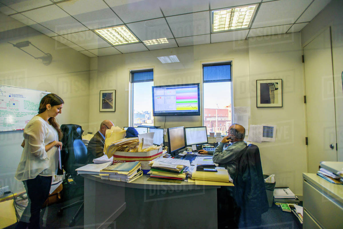 Three office workers at desks in office Stock Photo Dissolve