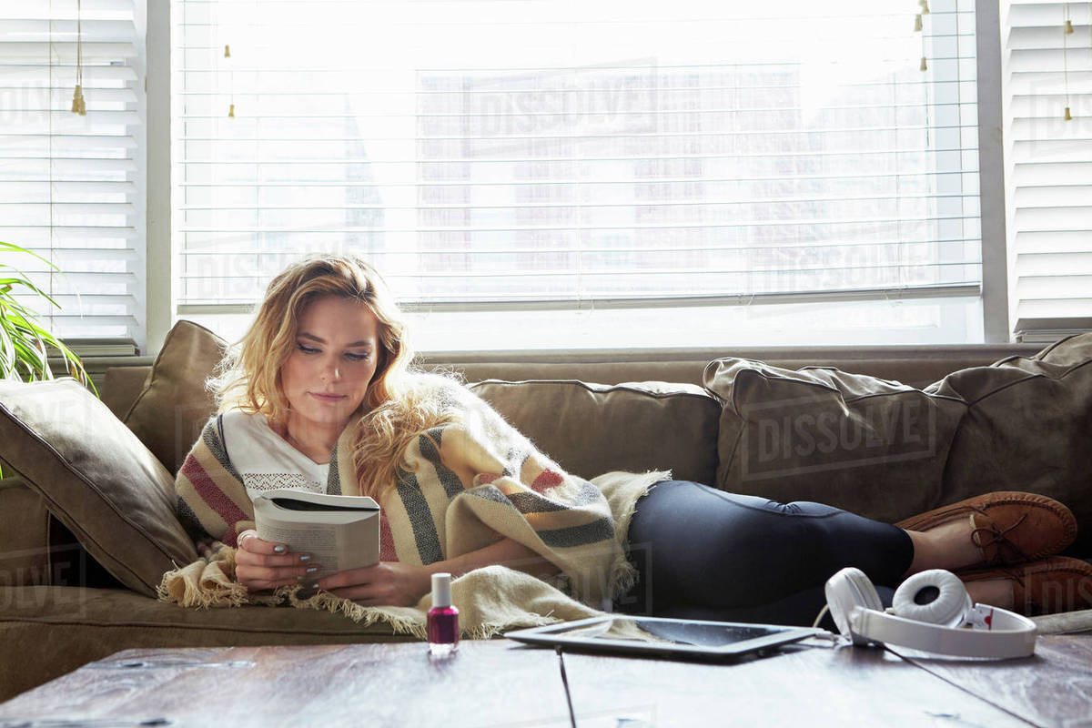 Woman Reading Book On Sofa Stock Photo Dissolve Woman Reading Book On Sofa