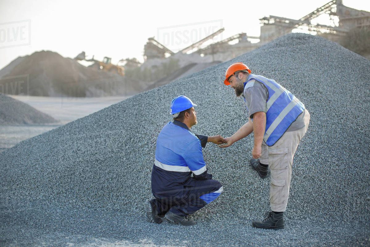 Two quarry workers in quarry, checking aggregate Stock Photo Dissolve
