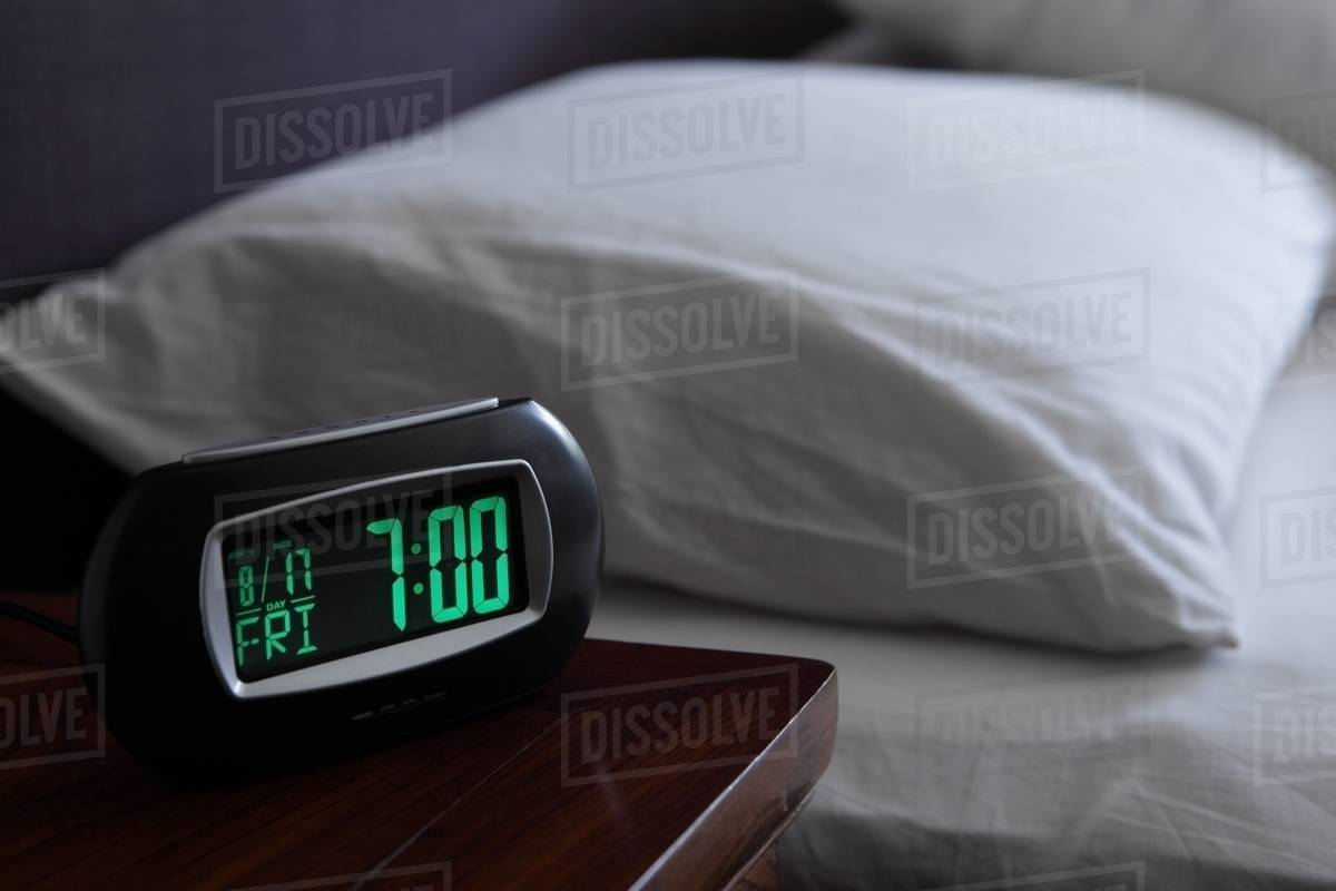 Alarm clock by bed Stock Photo Dissolve