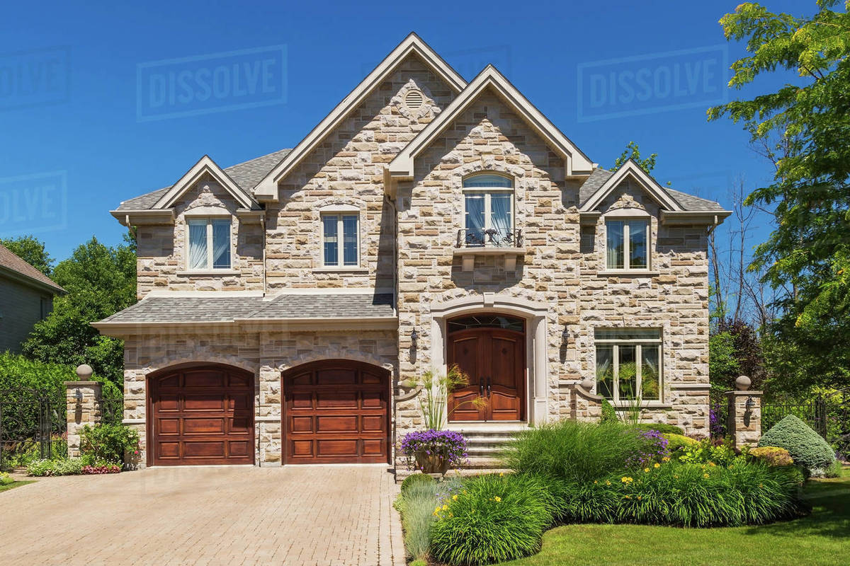 Facade of luxury house in cut stone with shrubs and flowers in garden border stock photo Facade of luxury house in cut stone with shrubs and flowers in garden border stock photo