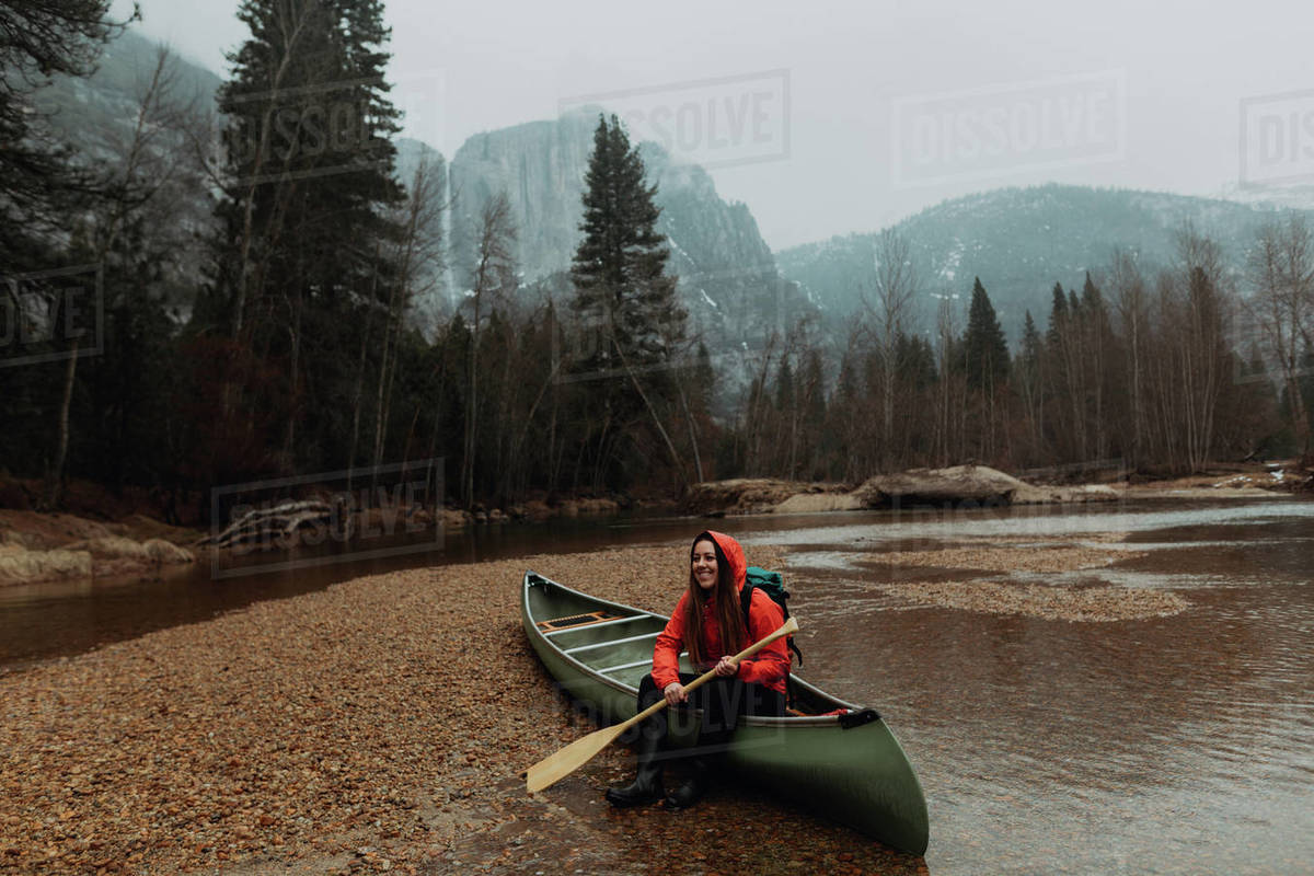 Happy young female canoeist sitting on canoe in river, Yosemite Village