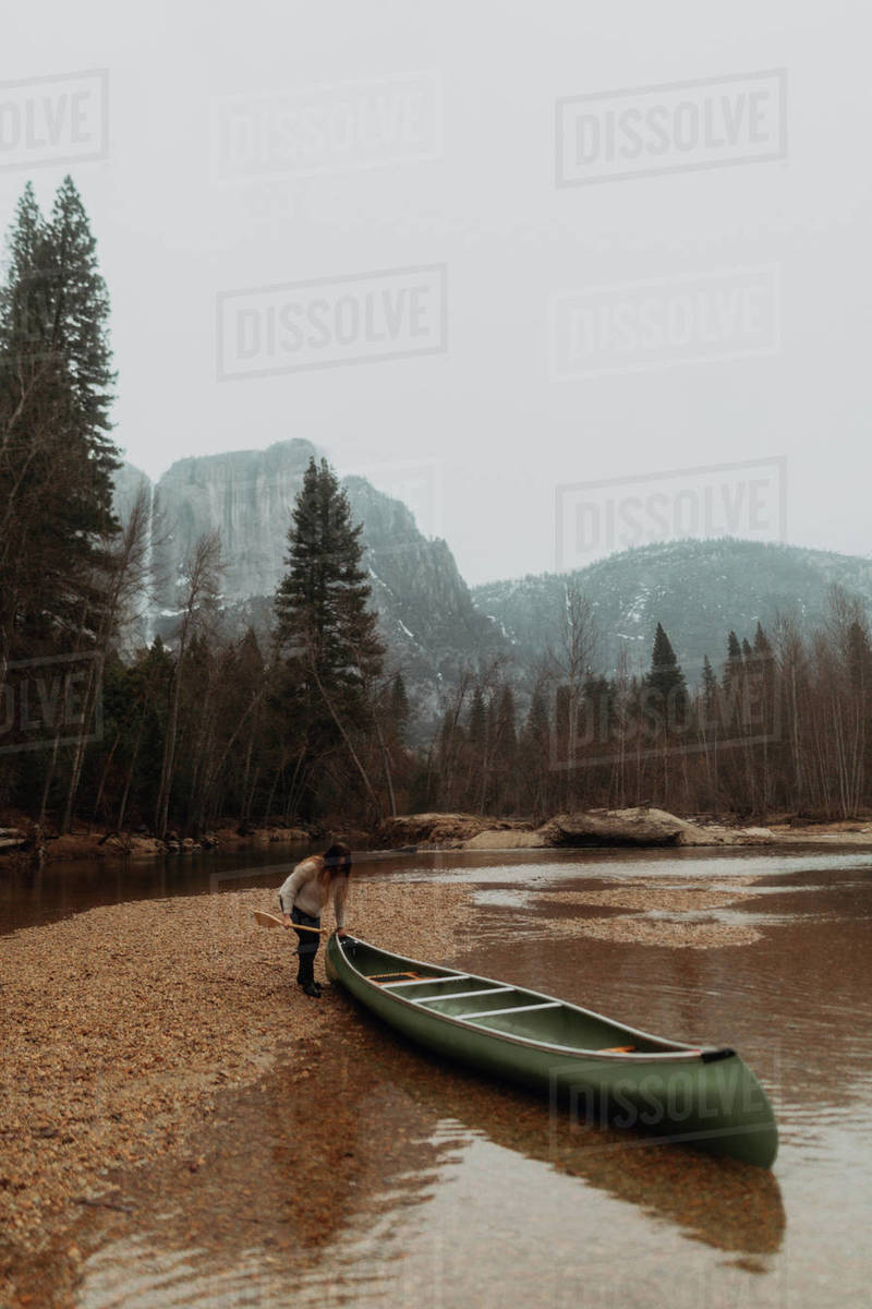 Young female canoeist pulling canoe from river, Yosemite Village