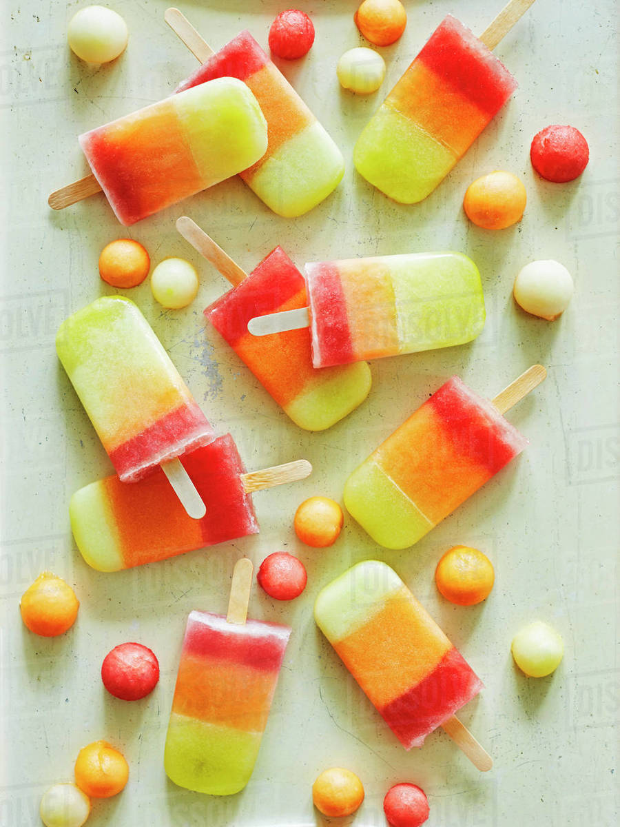 Tricoloured ice lollies and ice balls on table Stock Photo Dissolve
