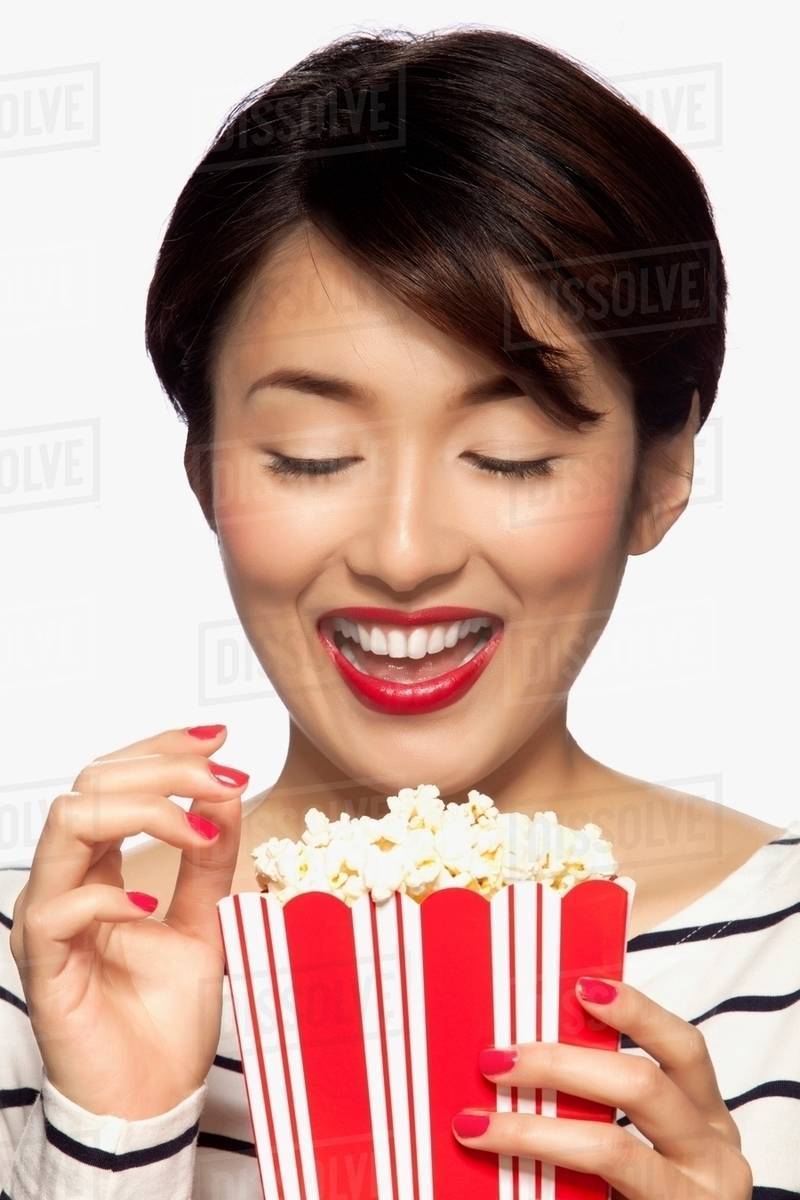 Young woman eating popcorn, studio shot Stock Photo Dissolve