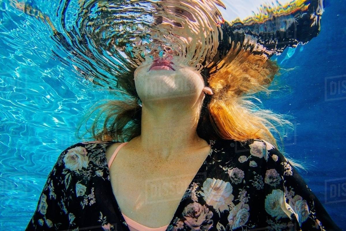 Young woman underwater, breaking through water surface Stock Photo