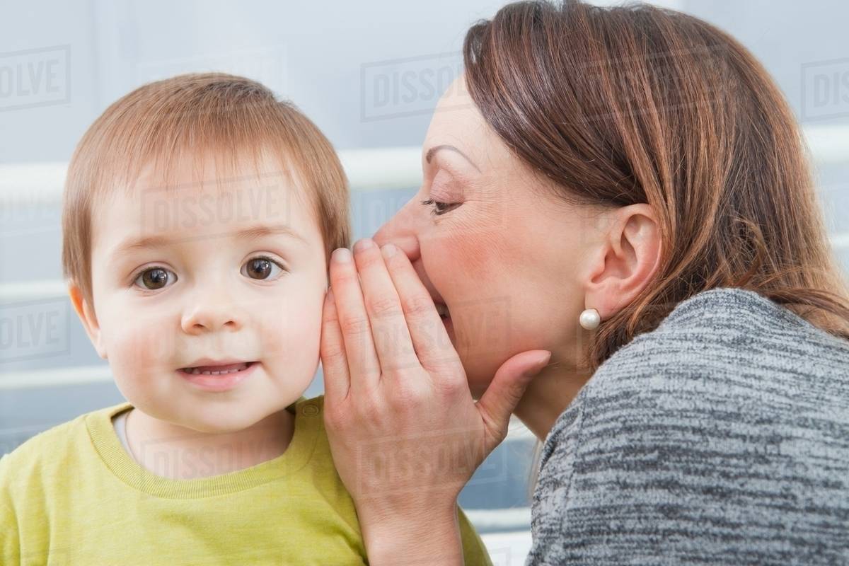Mother whispering into son's ear Stock Photo Dissolve