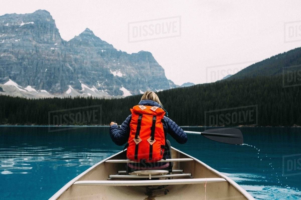 Rear view of mid adult woman paddling canoe, Moraine lake, Banff National Park, Alberta Canada Royalty-free stock photo