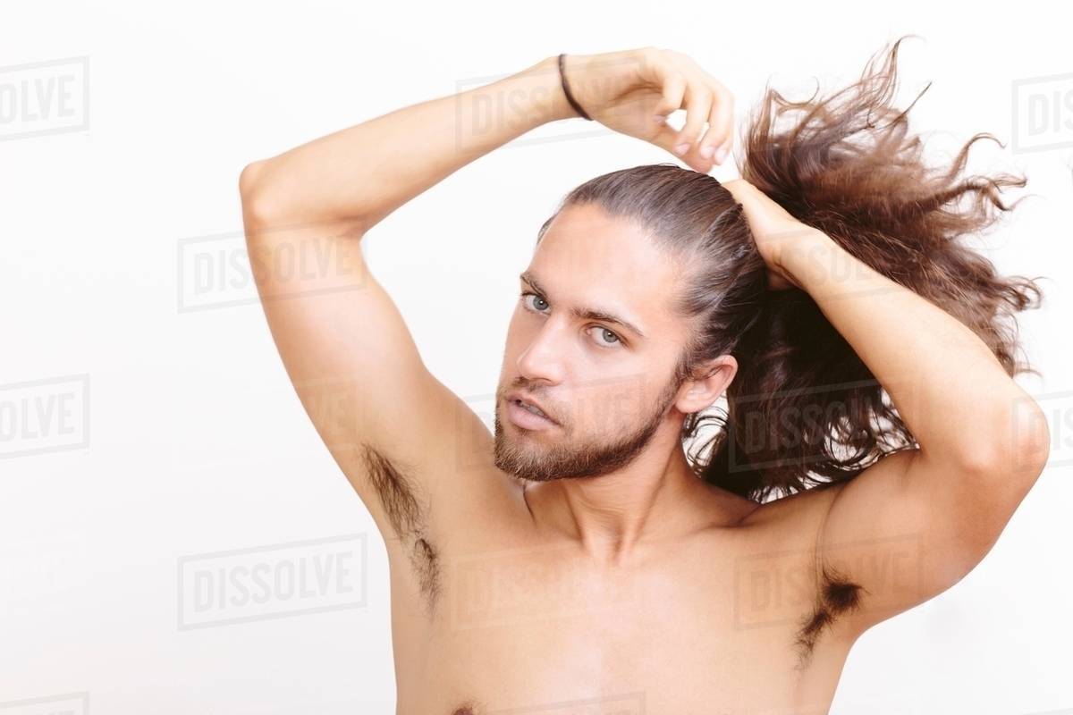Young man with long hair, putting hair in ponytail