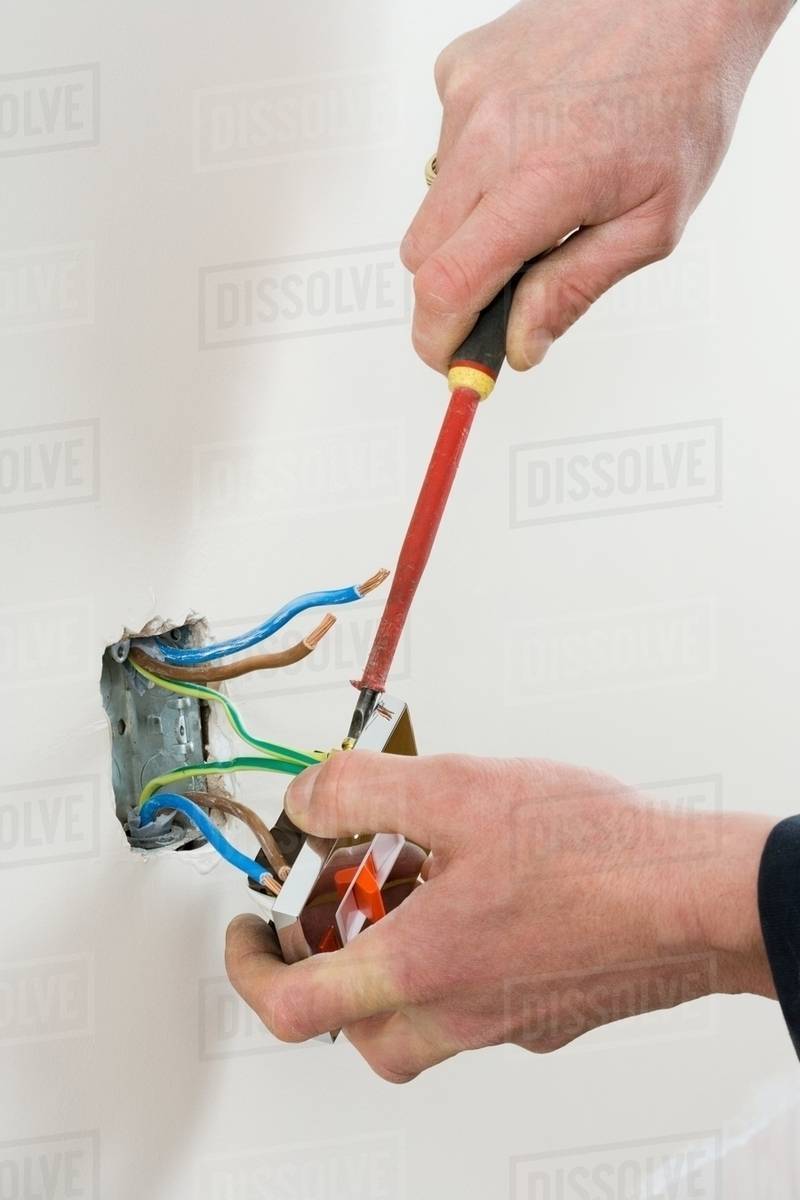 An electrician fixing a socket Stock Photo Dissolve