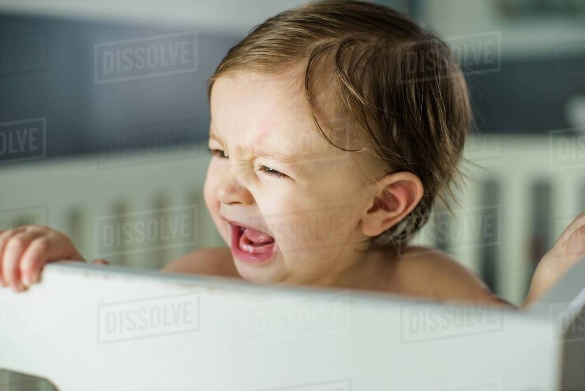 Head and shoulders of baby boy crying in crib Stock Photo Dissolve
