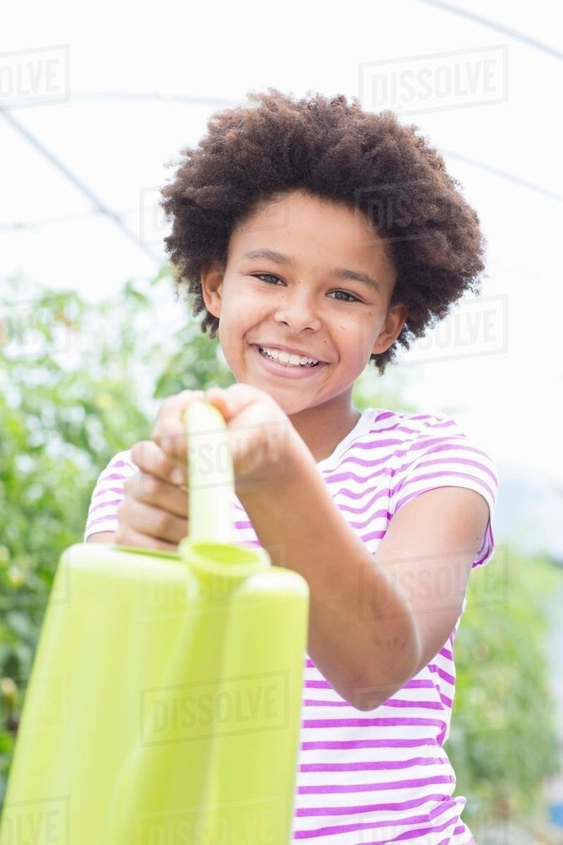 Girl holding green watering can Stock Photo Dissolve
